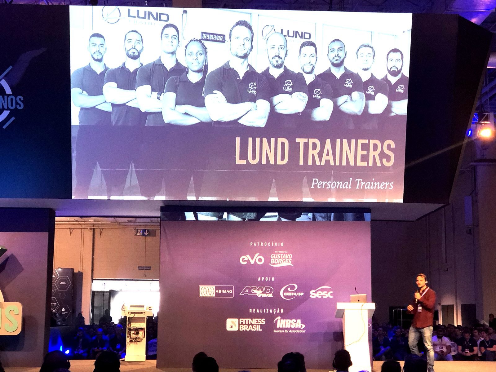 Rafa Lund palestrando na Fitness Brasil / IHRSA com o time Lund Trainers no telão